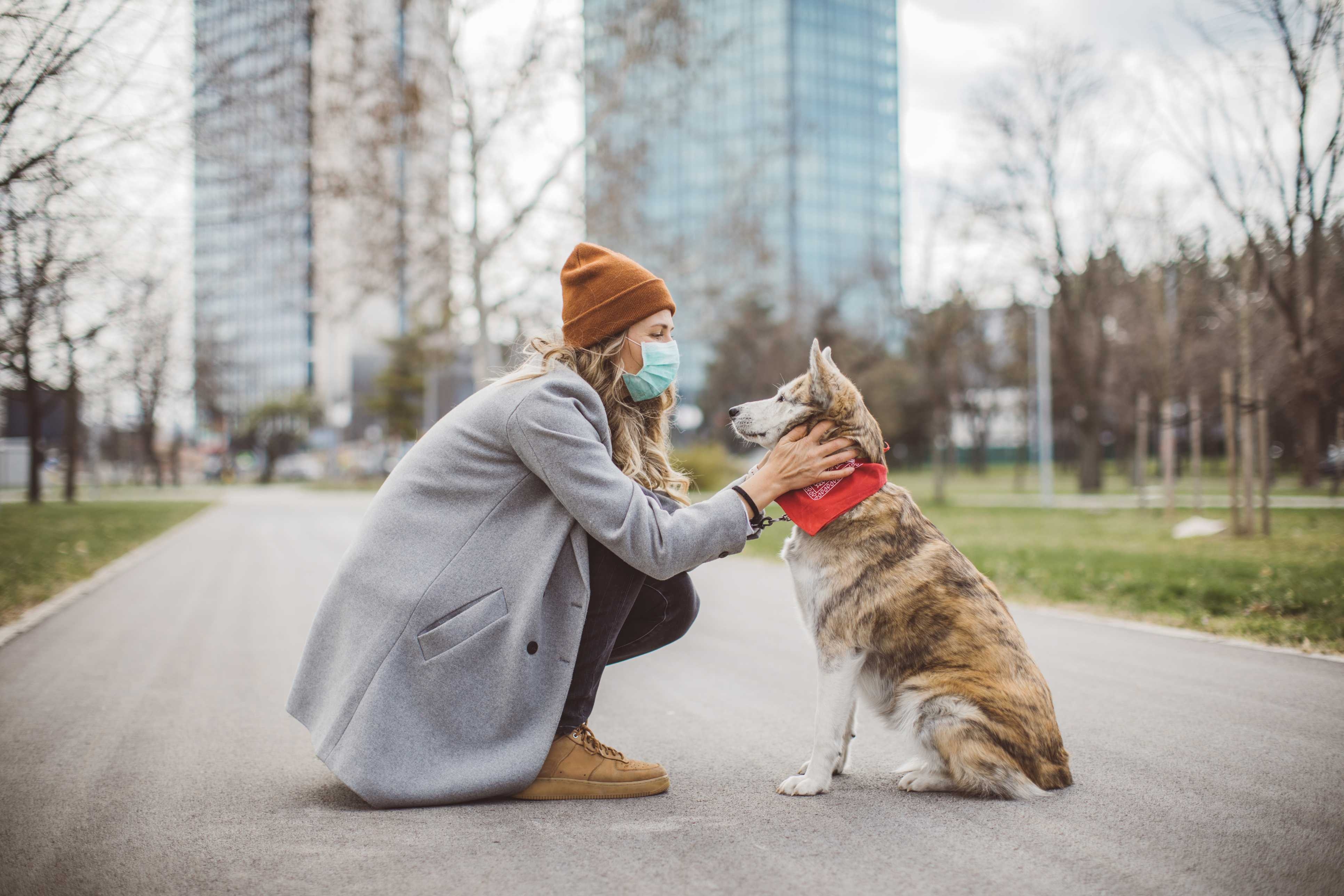 A woman petting her dog in the middle of the street