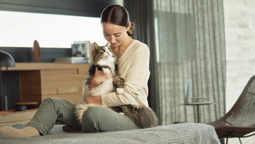 woman sitting on bed cuddling cat