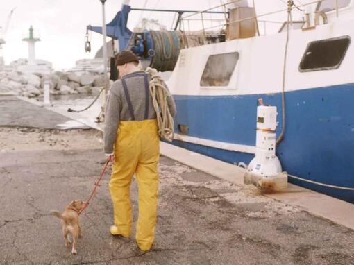 fisherman walking his dog next to fishing boat