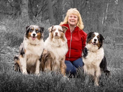 woman with 3 dogs sitting on the grass