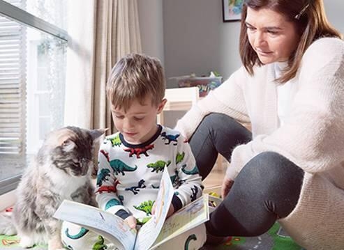 A mother and his child reading next to their cat
